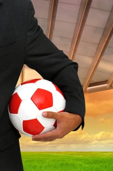 Businessman with soccer ball in a stadium like background