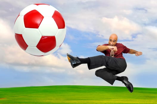 Businessman playing soccer outdoors in a green field