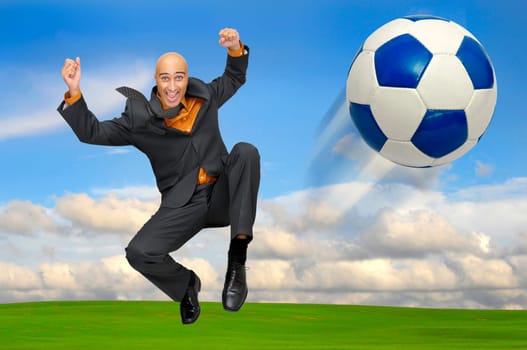 Businessman playing soccer outdoors in a green field