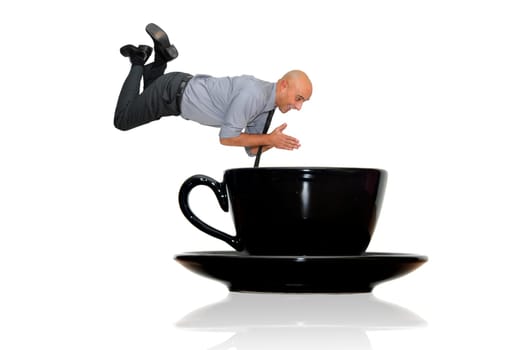 Businessman diving in to a coffee mug isolated in white