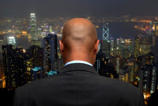 Businessman in the office looking at the city by night