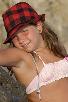 Beautiful young girl posing with hat in the beach