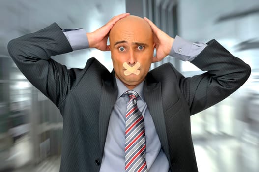 Distressed businessman with hands in his head and mouth covered with band aid