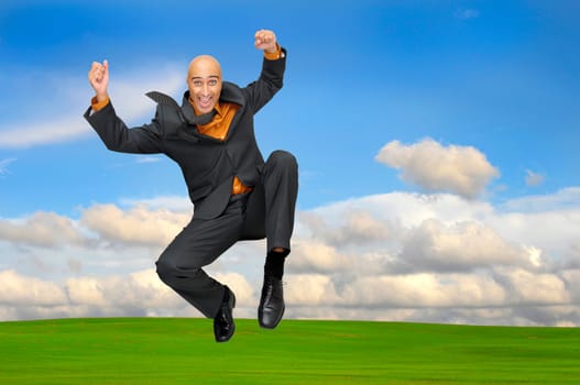 Businessman jumping outdoors in a green field