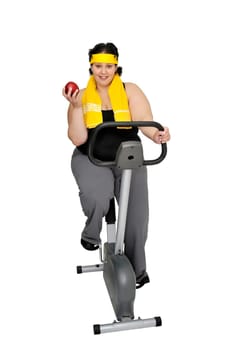 Large girl with fitness bicycle holding an apple isolated in white