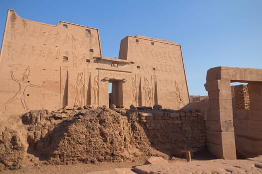 Pylon at Horus Temple with egyptian hieroglyphs. In the foreground are preserved walls that surrounded every temple in Egypt. But only in Edfu have been preserved to this day. ( Edfu, Egypt )