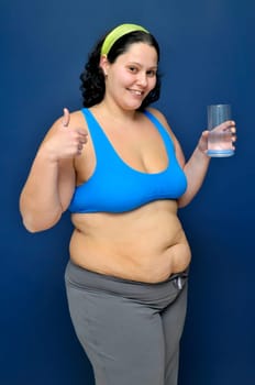 Large girl in fitness outfit with a glass of water
