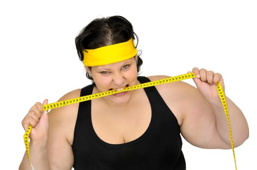 Angry large girl biting a measuring tape isolated in white