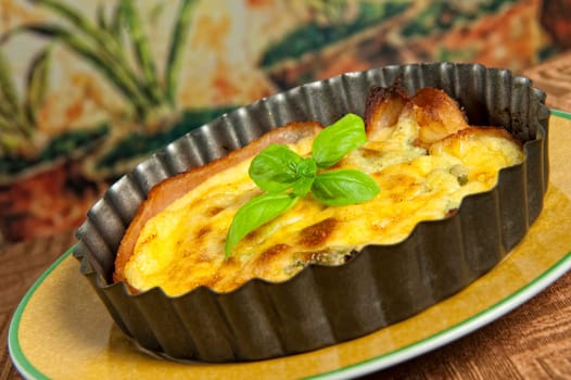 Eggs and bacon tart with basil leaves