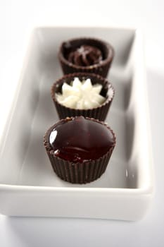 Three little chocolate cakes in a line with cream and strawberry  jam