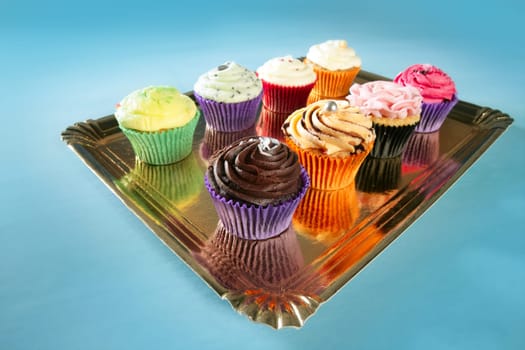 Cupcakes colorful cream muffin arrangement in golden mirror tray