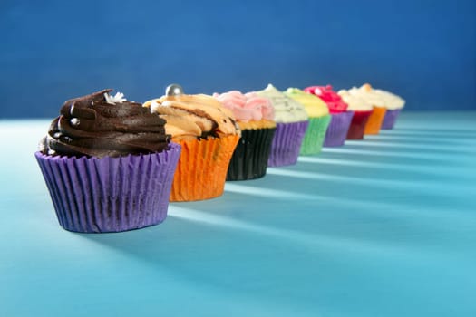 Cupcakes colorful cream muffin arrangement in a row line on turquoise