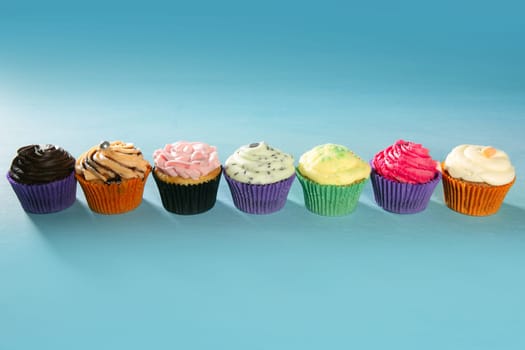 colorful cupcakes arrangement in a row on turquoise studio background