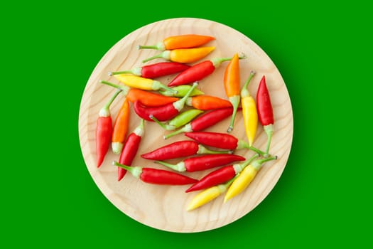 colorful chili peppers plate isolated on green background