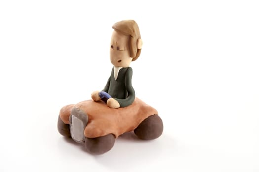 Handmade plasticine man driving a car isolated on white