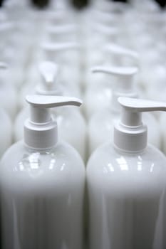 White plastic soap bottles in rows, cosmetics laboratory assembly line