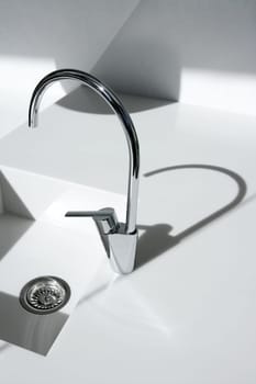 White modern kitchen detail, faucet and sink with shadows