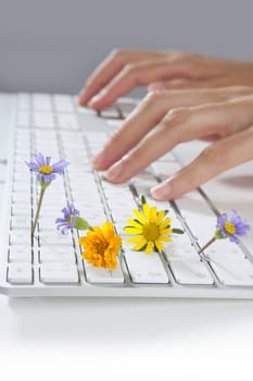 Ecology concept of woman hands typing a keyboard with flowers