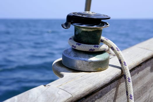 Sail boat winch with marine rope arround. Wooden sailboat