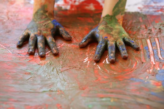 Children artist hands painting multi color with her fingers