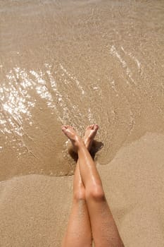 Children girl legs in beach sand shore at summer vacation