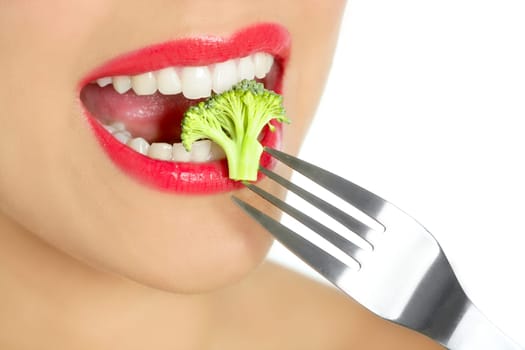 Broccoli on steel fork in woman mouth with red lips