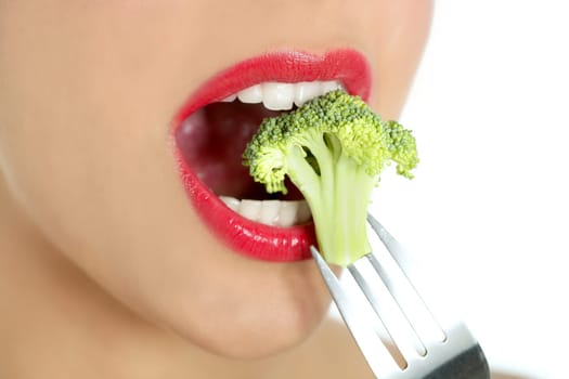 Broccoli on steel fork in woman mouth with red lips