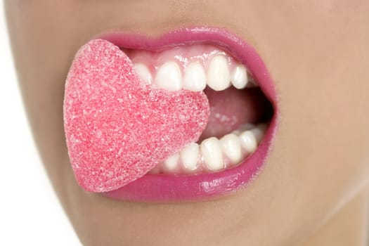Heart shape candy on beautiful woman macro mouth
