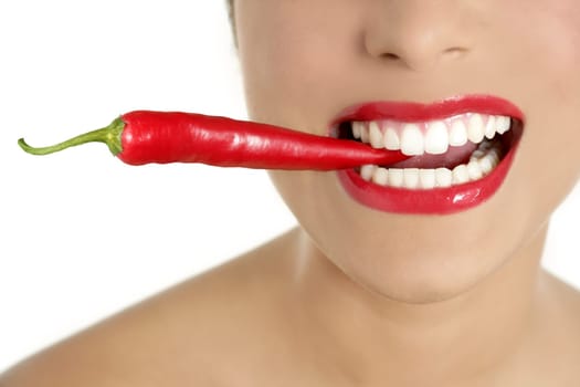 Beautiful woman teeth eating red hot chili pepper