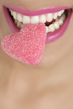 Heart shape candy on beautiful woman macro mouth
