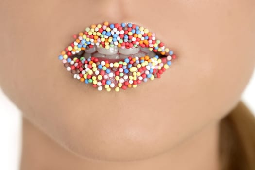 close up of woman lips with multicolored sweet pearls