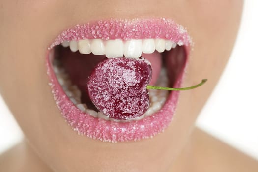 Cherry with sugar lips between woman perfect teeth macro mouth