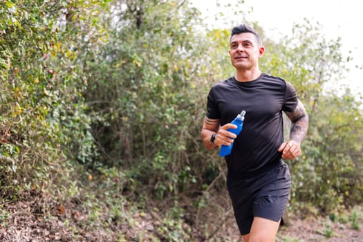 portrait of a man practicing trail running in the forest, concept of sport in nature and healthy lifestyle, copy space for text