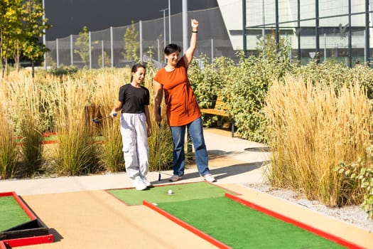 Mother and her little daughter practicing to hit the ball at the course. High quality photo