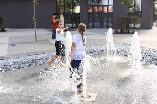 On a hot day, children run and have fun at the city fountain. Leisure time concept. summer holidays. happy childhood. High quality photo