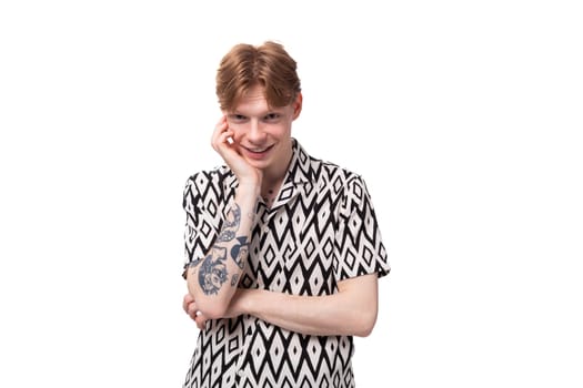 young smiling red-haired man dressed in a summer short-sleeved shirt in black and white.