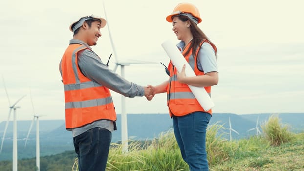 Male and female engineers working on a wind farm atop a hill or mountain in the rural. Progressive ideal for the future production of renewable, sustainable energy.