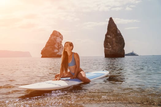 Close up shot of beautiful young caucasian woman with black hair and freckles looking at camera and smiling. Cute woman portrait in a pink bikini posing on a volcanic rock high above the sea