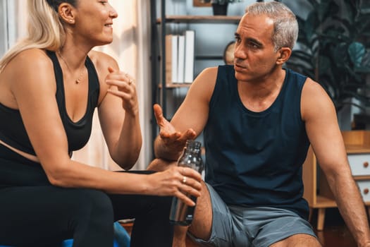 Athletic and sporty senior couple portrait in sportswear sitting on sofa as home exercise concept. Healthy fit body lifestyle after retirement. Clout