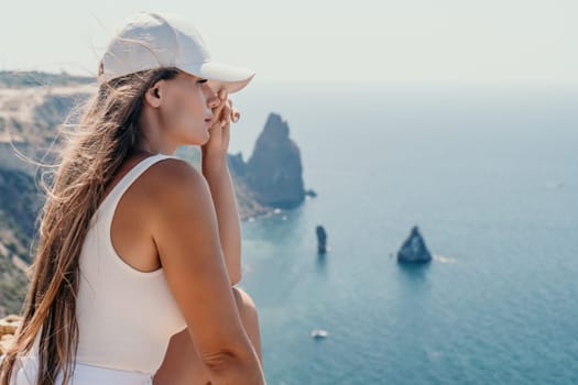 Woman travel sea. Young Happy woman in a long red dress posing on a beach near the sea on background of volcanic rocks, like in Iceland, sharing travel adventure journey