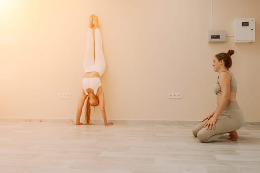 Group of young womans fitness instructor in Sportswear Leggings and Tops, stretching in the gym before pilates, on a yoga mat near the large window on a sunny day, female fitness yoga routine concept.