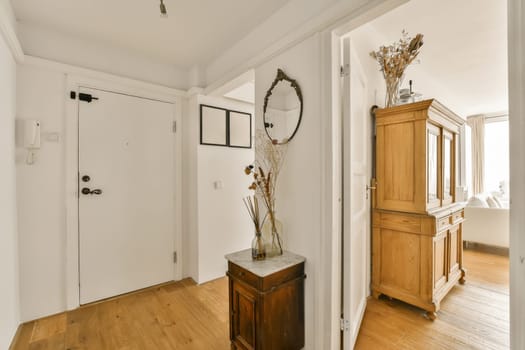 a room with wood floors and white walls, including a mirror on the wall in the door is open to an entry way