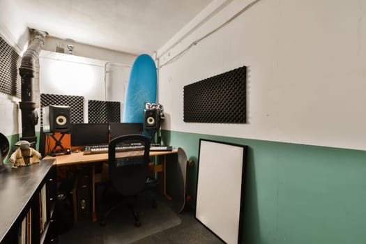 a room with a surfboard on the wall next to a computer desk and two chairs in front of it