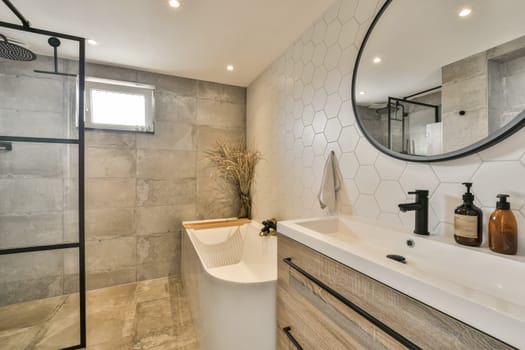 a modern bathroom with hexagon tiles on the walls, and a large mirror in the corner of the room