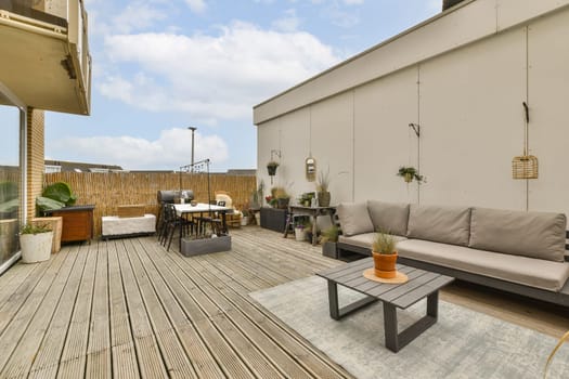 an outdoor living area with wood flooring and wooden furniture on the outside deck looking out to the backyard garden