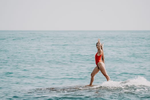 Woman sea yoga. Back view of free calm happy satisfied woman with long hair standing on top rock with yoga position against of sky by the sea. Healthy lifestyle outdoors in nature, fitness concept.