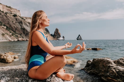 Woman sea yoga. Back view of free calm happy satisfied woman with long hair standing on top rock with yoga position against of sky by the sea. Healthy lifestyle outdoors in nature, fitness concept.