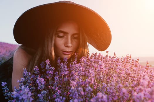 Close up portrait of young beautiful woman in a white dress and a hat is walking in the lavender field and smelling lavender bouquet.