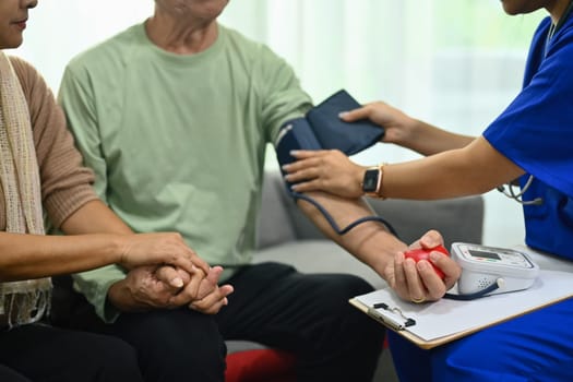 Cropped shot of health visitor measuring blood pressure senior man at home. Elderly healthcare concept.