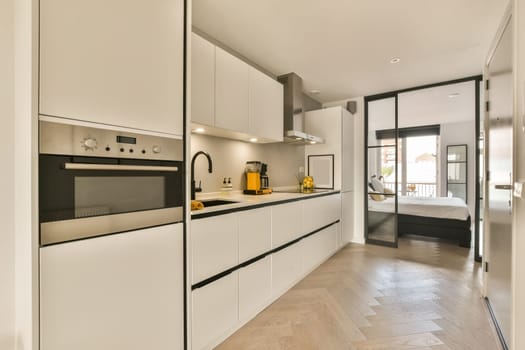 a modern kitchen with white cabinets and black appliances on the counter tops, in an open space that has wood flooring